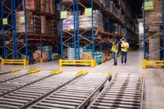 Warehouse workers checking inventory and goods distribution in large storehouse.